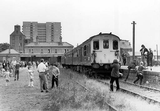[PHOTO: Train and people at overgrown station: 35kB]