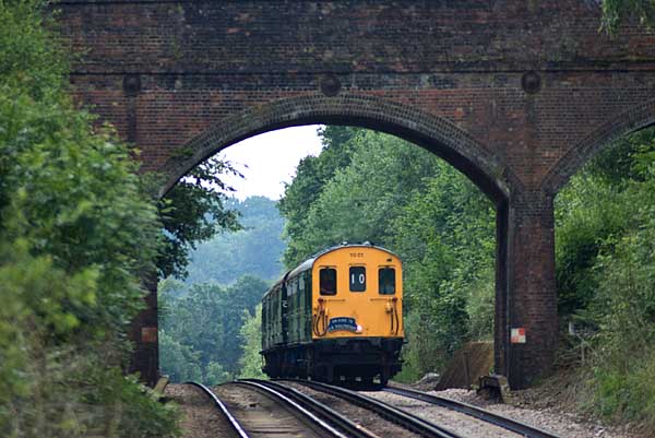 [PHOTO: Train approaching over summit and beneath bridge: 44kB]