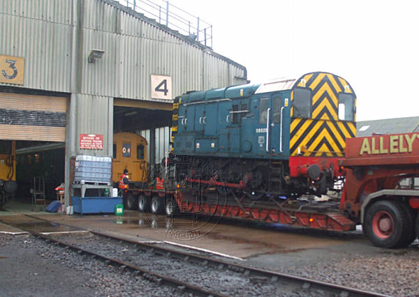 [PHOTO: Railway loco on low-loader in depot yard: 50kB]
