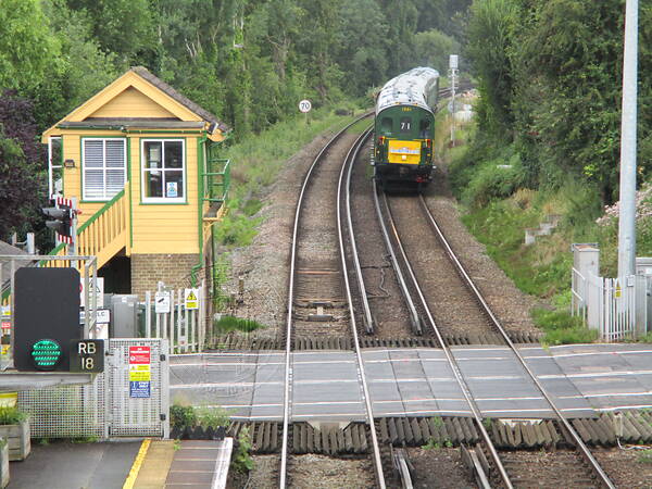 [PHOTO: Train approaching level crossing with signal-box: 69kB]